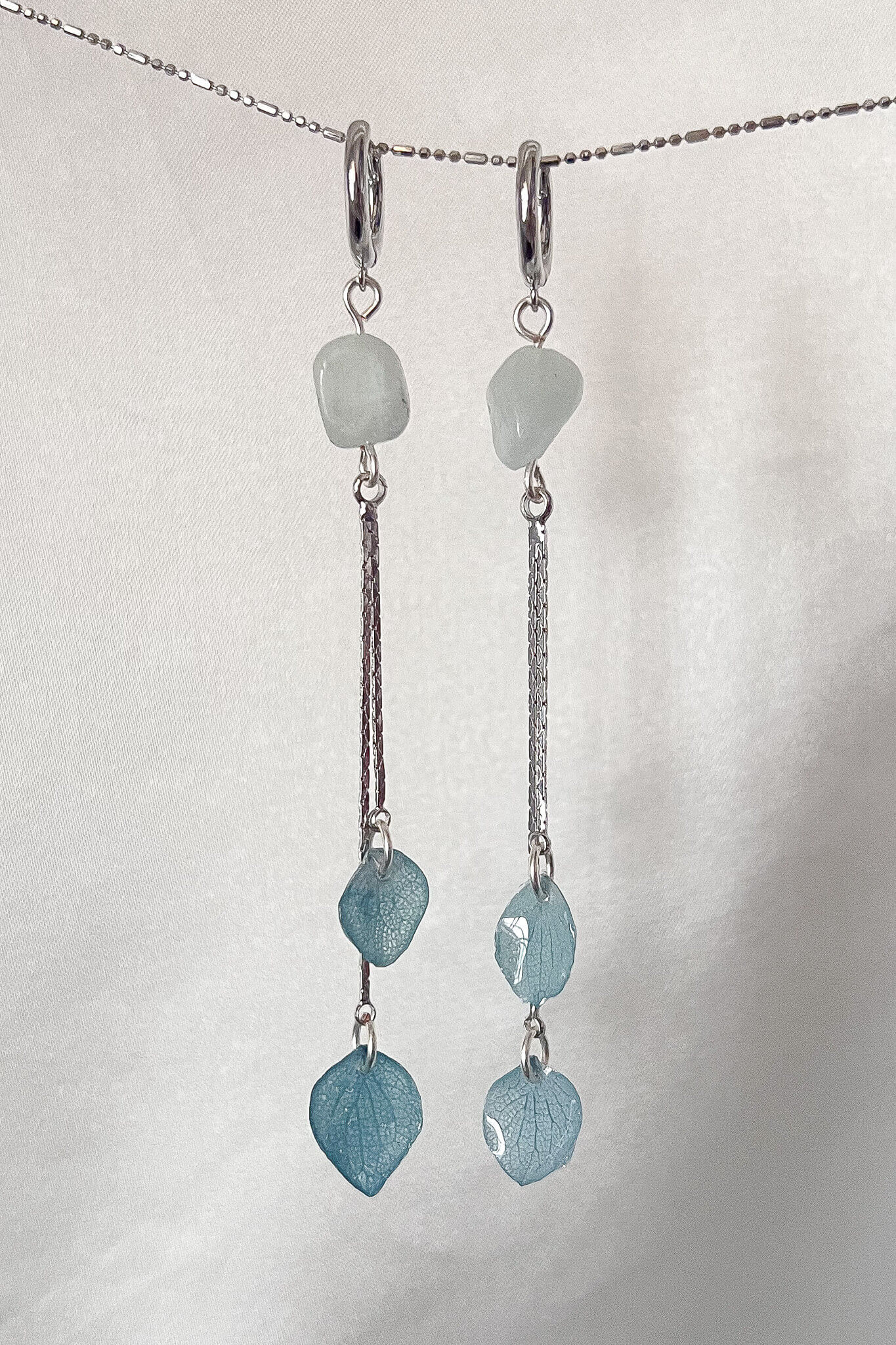 These earrings feature a crystal piece and delicately dangling preserved hydrangea petals, making them the perfect combination of simple elegance. These earrings will add a unique touch to any look! Silver hardware 