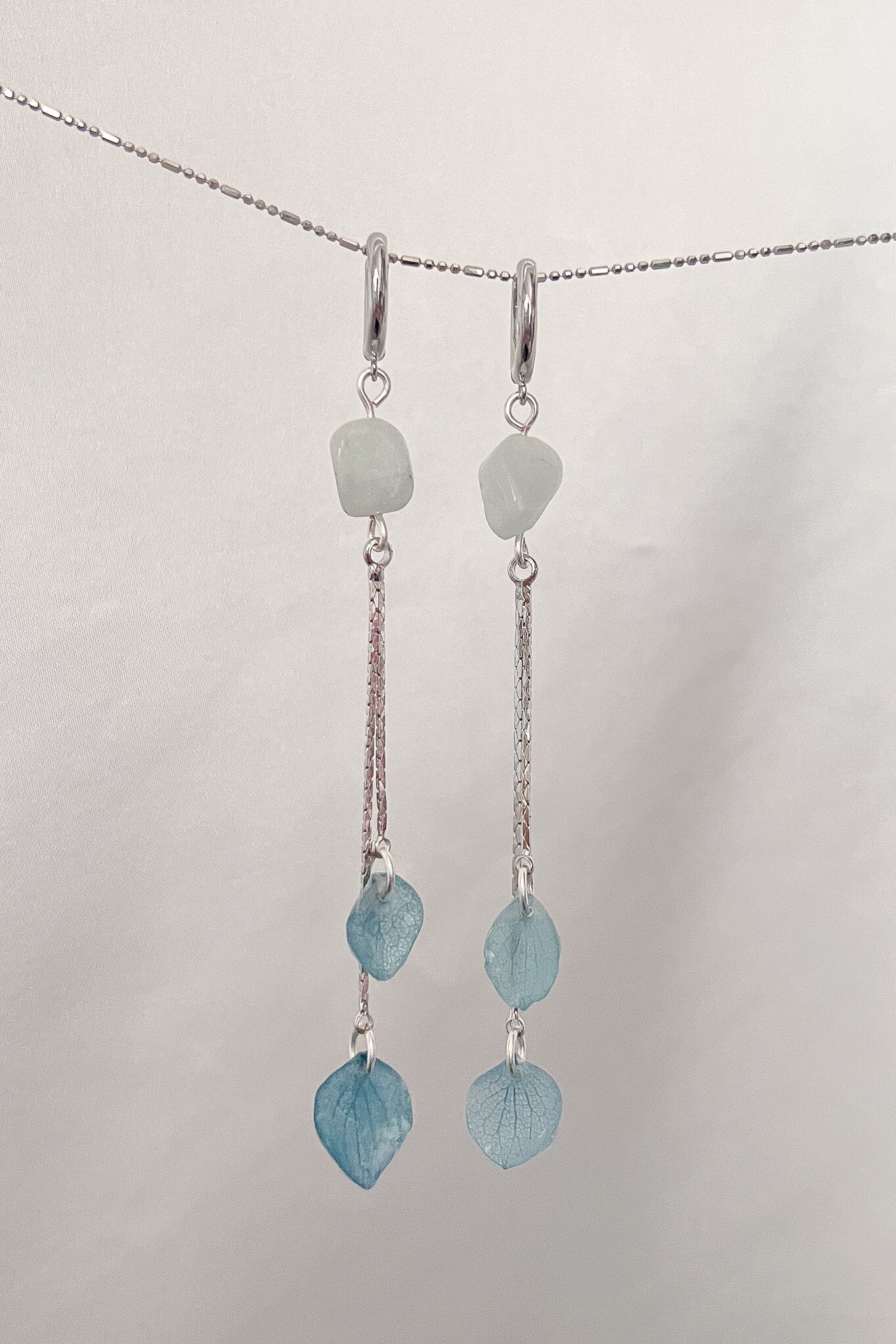 These earrings feature a crystal piece and delicately dangling preserved hydrangea petals, making them the perfect combination of simple elegance. These earrings will add a unique touch to any look!