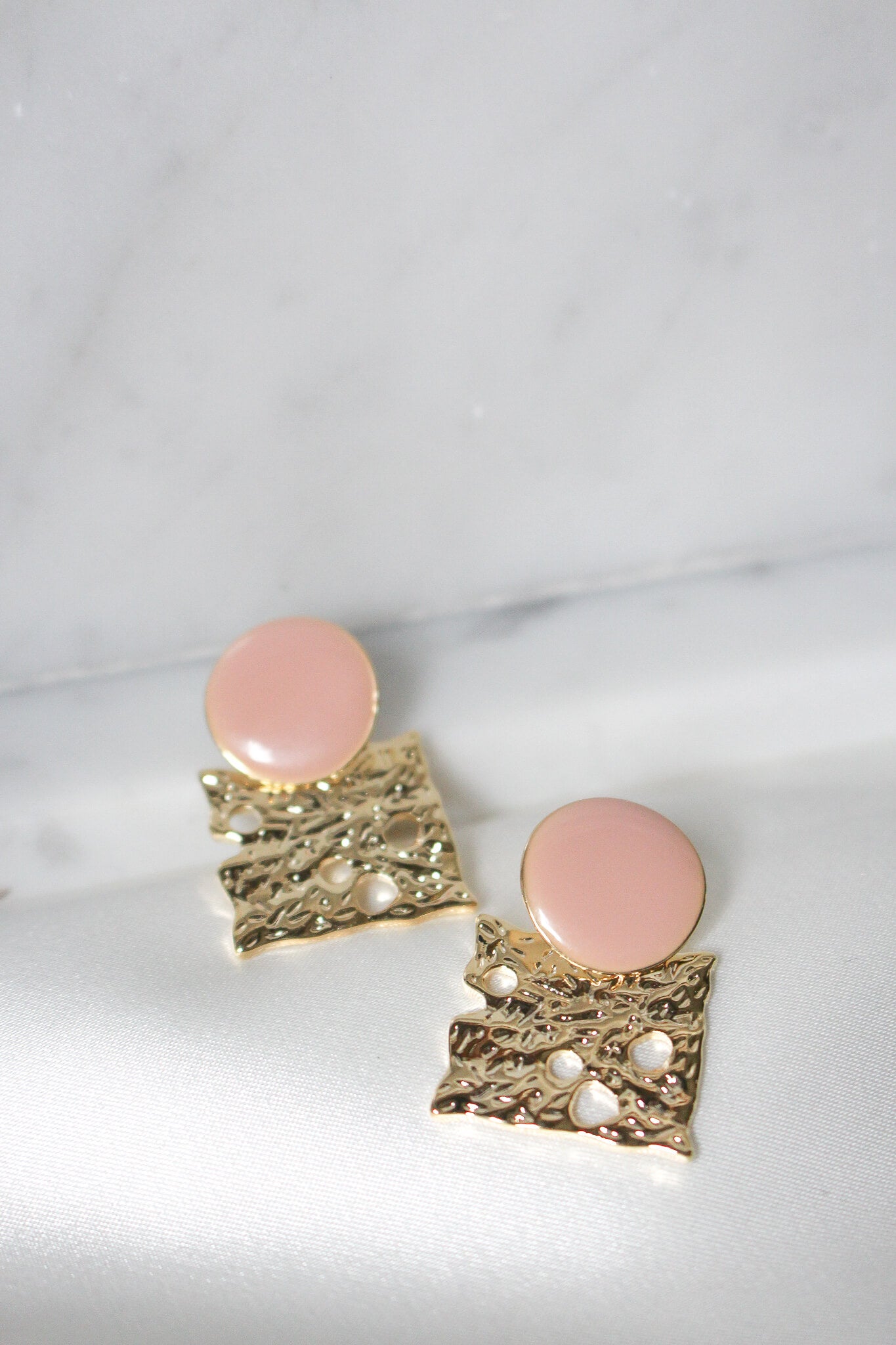 Gold and peach pink earrings, looks like cheese.