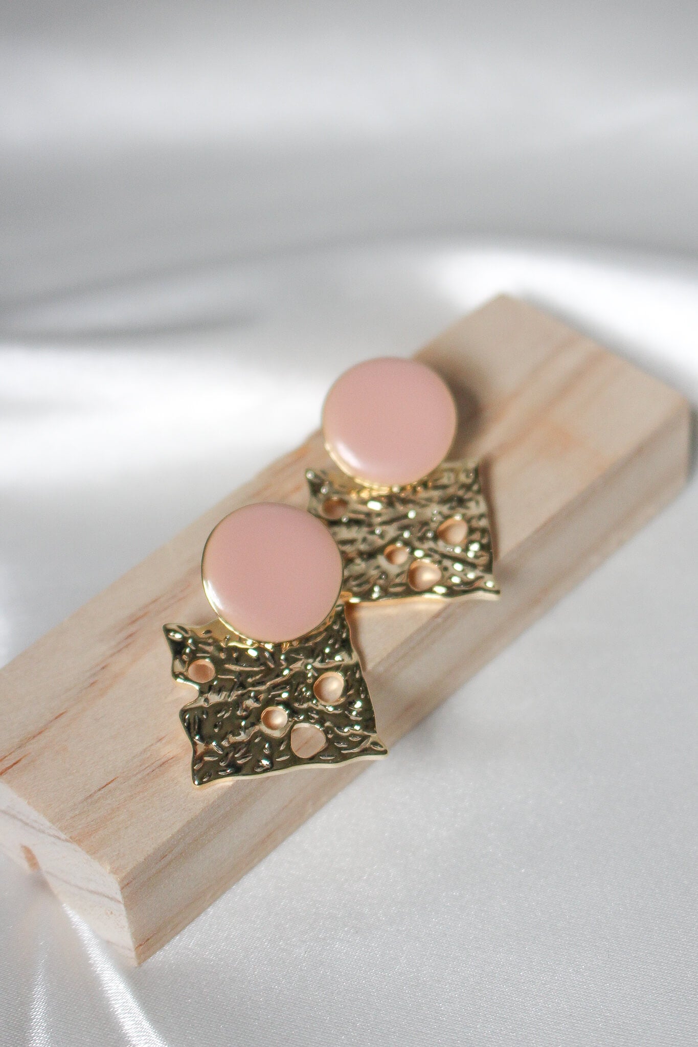 Gold and peach pink earrings, looks like cheese.