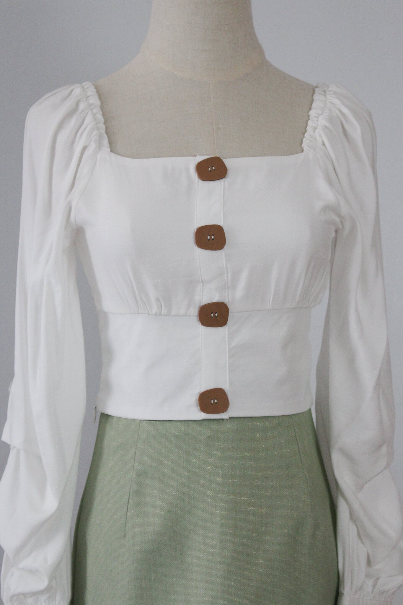 A square neck cropped top with long puffed sleeves. Complete with wooden finish buttons. 
